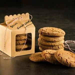 Bacon Fat Gingersnaps stacked on table next to a gift box