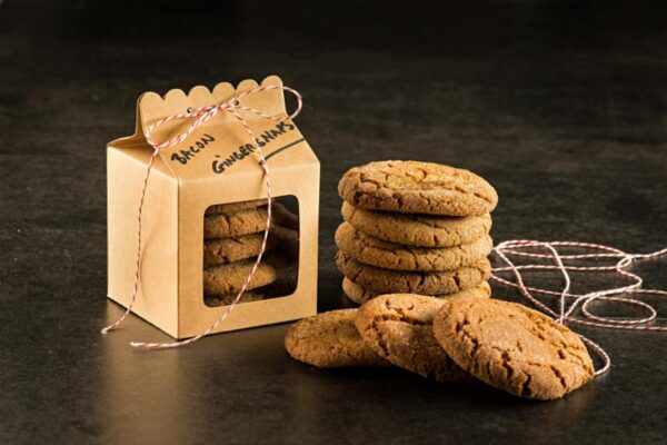 Bacon Fat Gingersnaps stacked on table next to a gift box