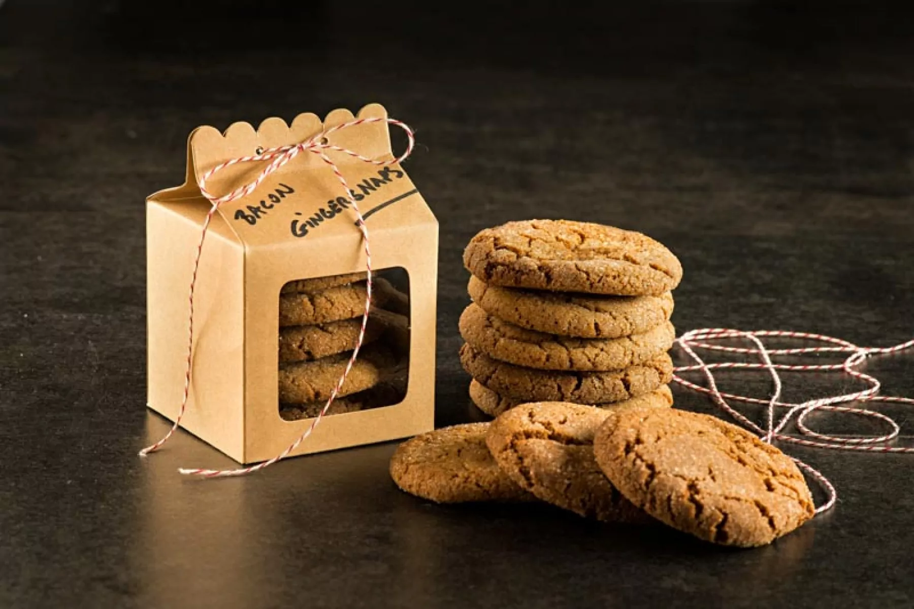 Bacon Fat Gingersnaps stacked on table next to a gift box