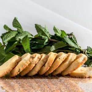 Lemon Cookies with White Chocolate and Mint stacked on a table with fresh mint.