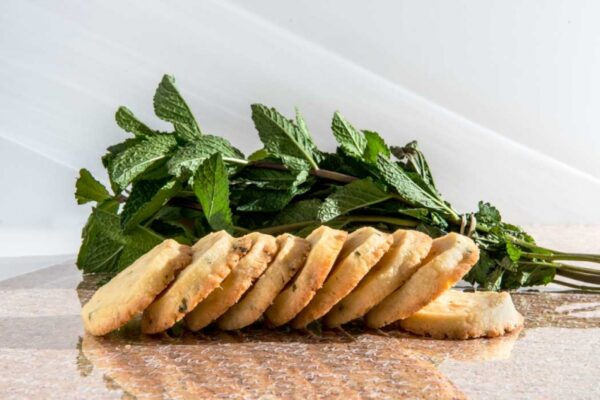 Lemon Cookies with White Chocolate and Mint stacked on a table with fresh mint.