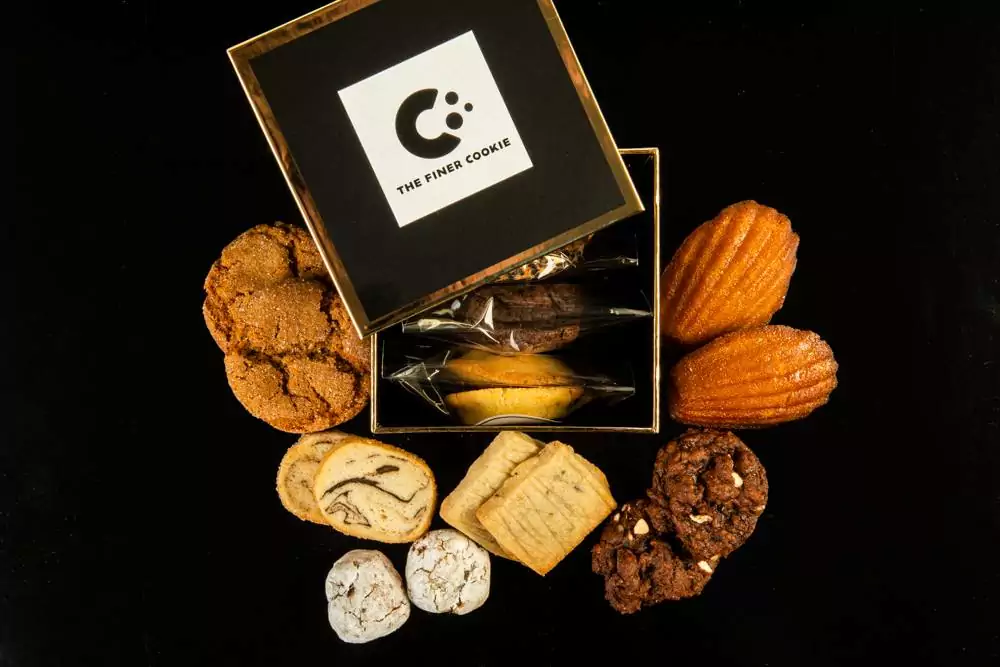 Individually Wrapped Cookies in Signature Gift Box placed on a table with cookies placed around the box.