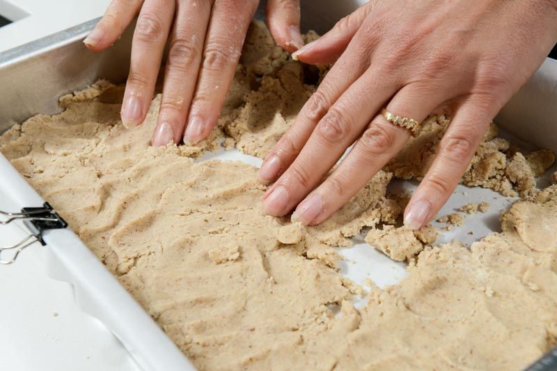 Pressing the walnut shortbread into the prepared pan.