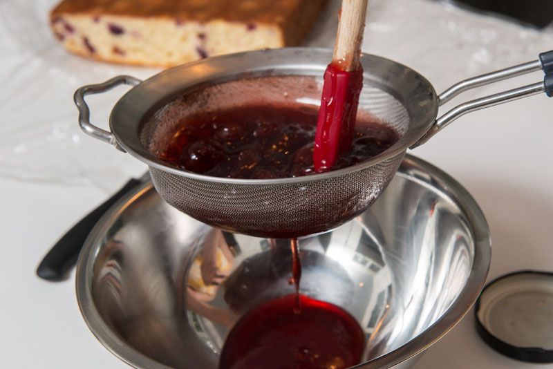 Straining the cherry jam through a fine sieve.