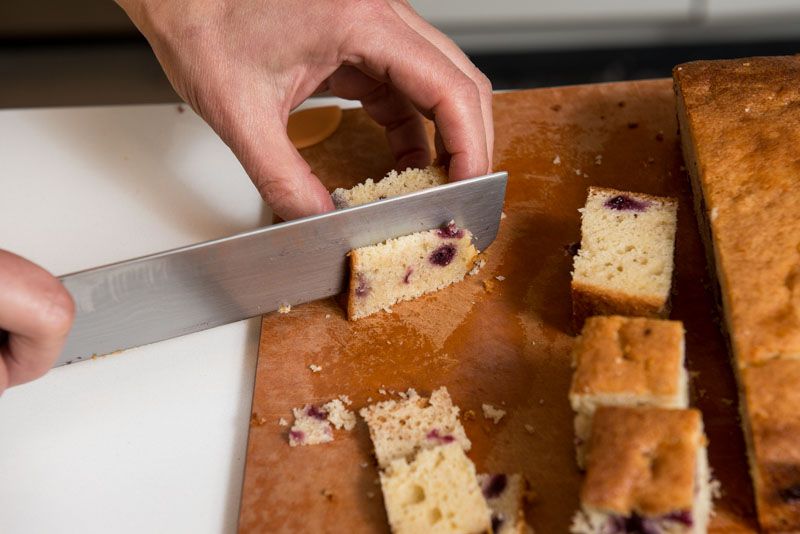 Trimming the cake into squares and cutting away the crusts.