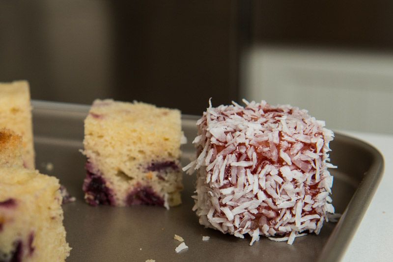 Coating the cakes with cherry jam and coconut.