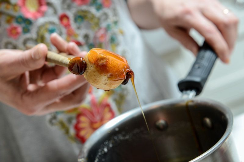 Dipping half the choux into the hot sugar.