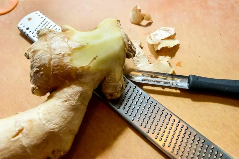 Grating fresh ginger to extract the ginger juice.