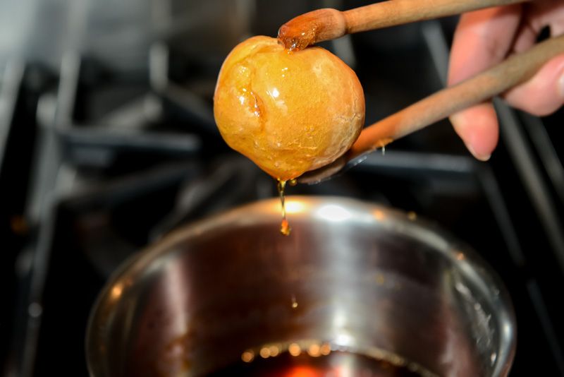 Dipping the pâte-à-choux into the caramelized sugar.