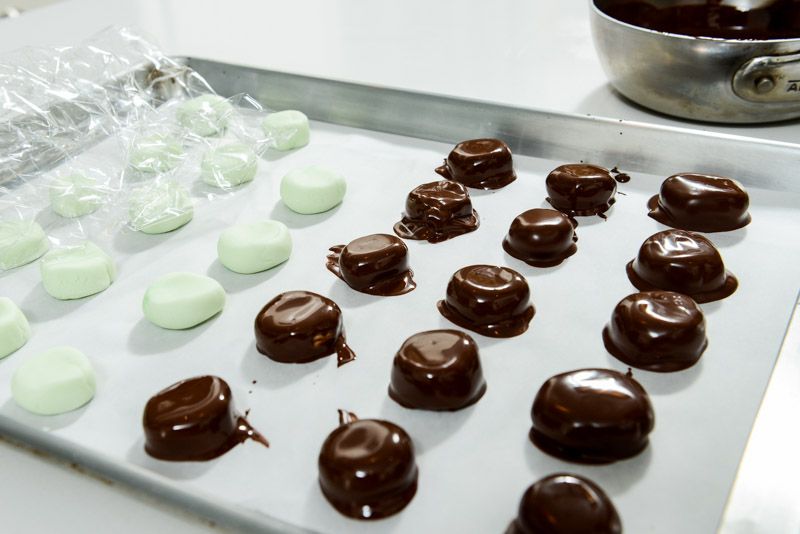 Coat each peppermint patty in melted chocolate.