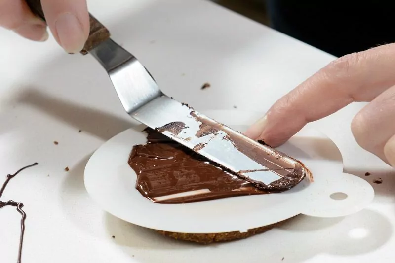 With the lightest touch, smooth the chocolate over the stencil.