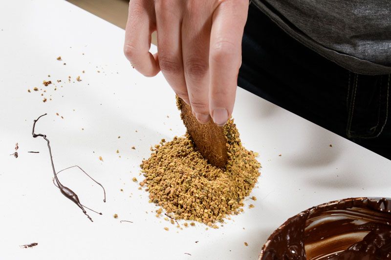 Rolling the wet chocolate edge in ground pistachios.