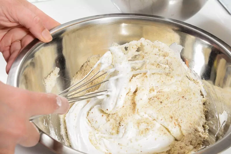 Folding the almond flour and sugar to make the batter.