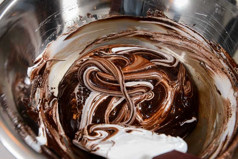 Folding melted chocolate into Italian meringue.
