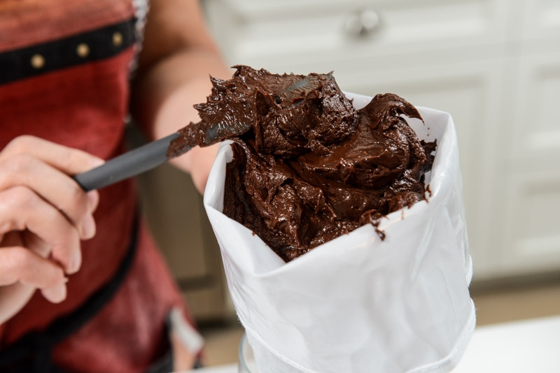 Spooning the chocolate ganache into the prepared pastry bag.