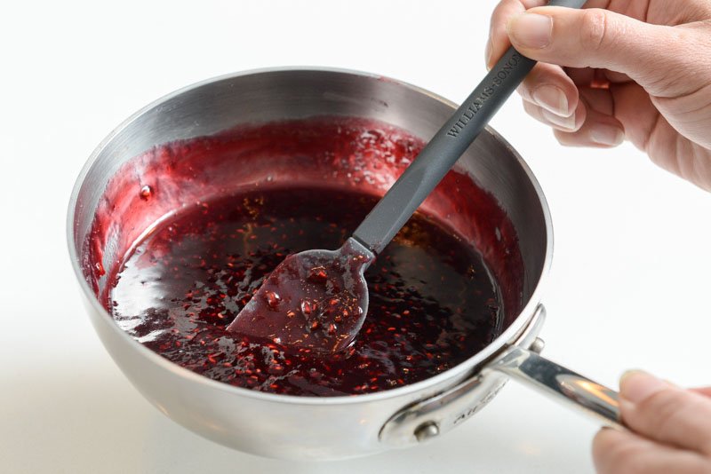 Gentle heat will loosen the jam in order to strain the seeds away.