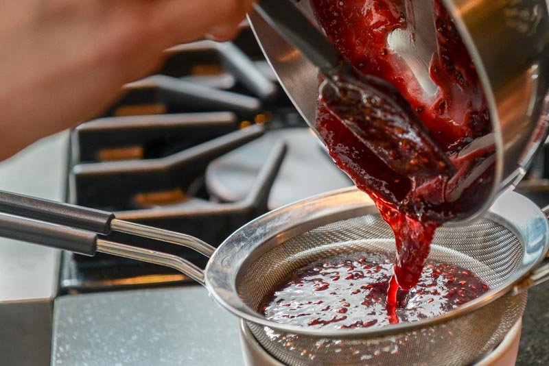 Straining the seeds out of the raspberry jam ensures an even coat.