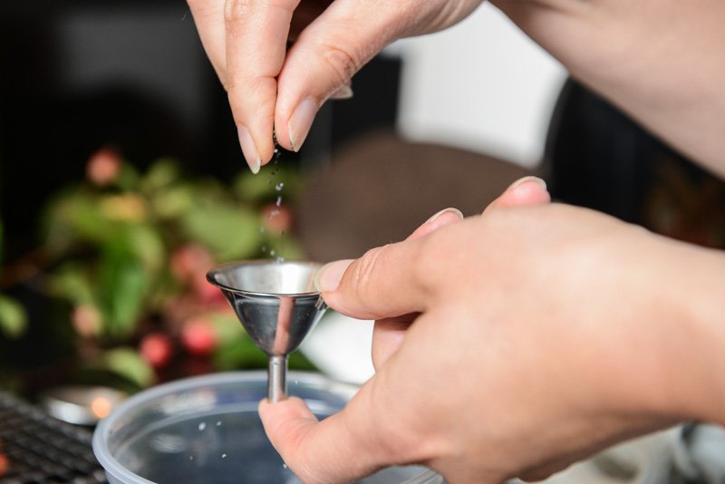 Block the flow of poppy seeds from the funnel with your finger.