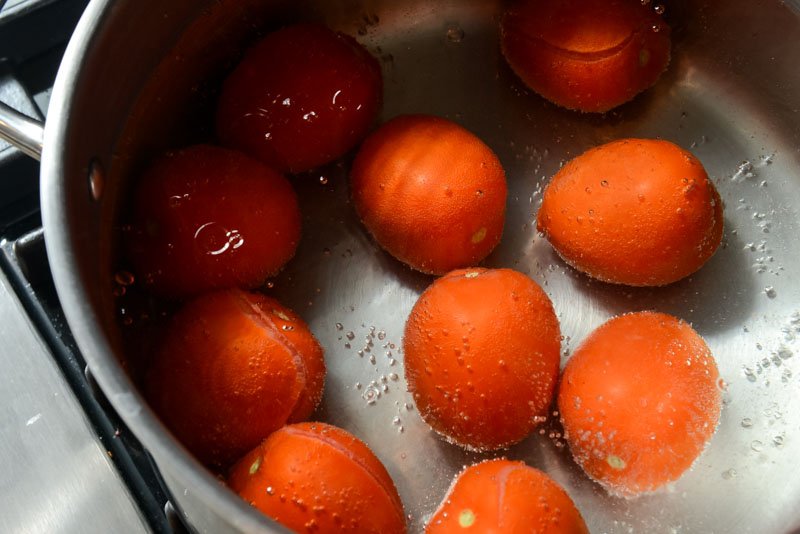 Removing tomato skins by submerging them in boiling water.