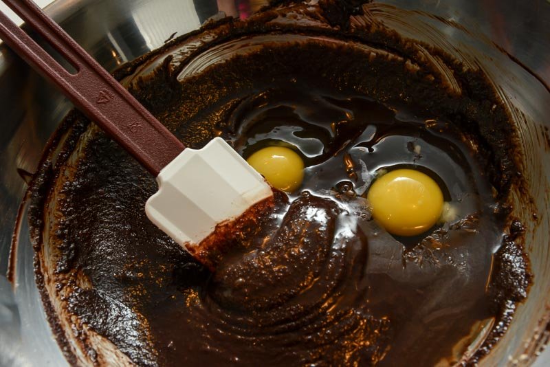 Adding the eggs to the chocolate and sugar.