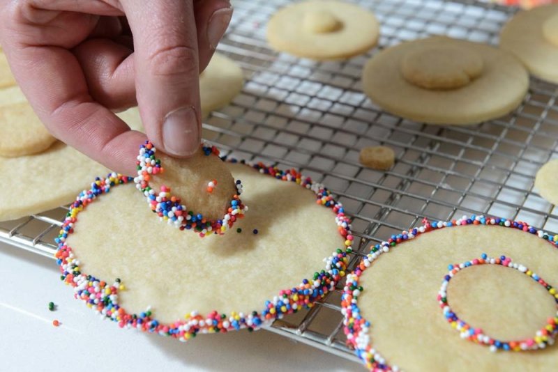 Setting the smaller cookie onto the larger cookie.