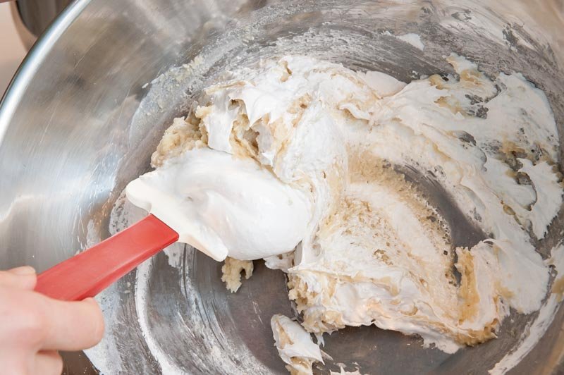 Adding the whipped meringue to the macaron almond paste.