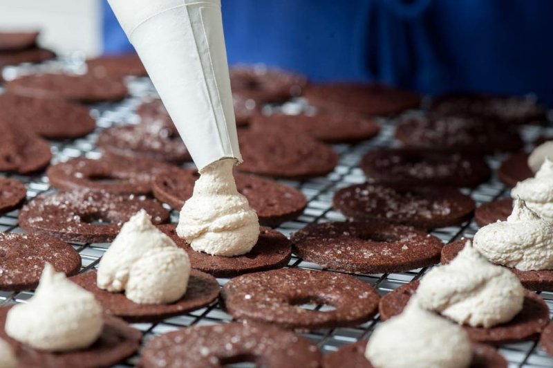 Piping the malted milk butter cream onto the cookies.