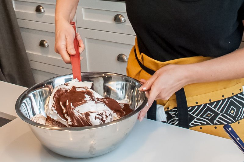 Folding the dry, unsweetened cocoa powder into the meringue.