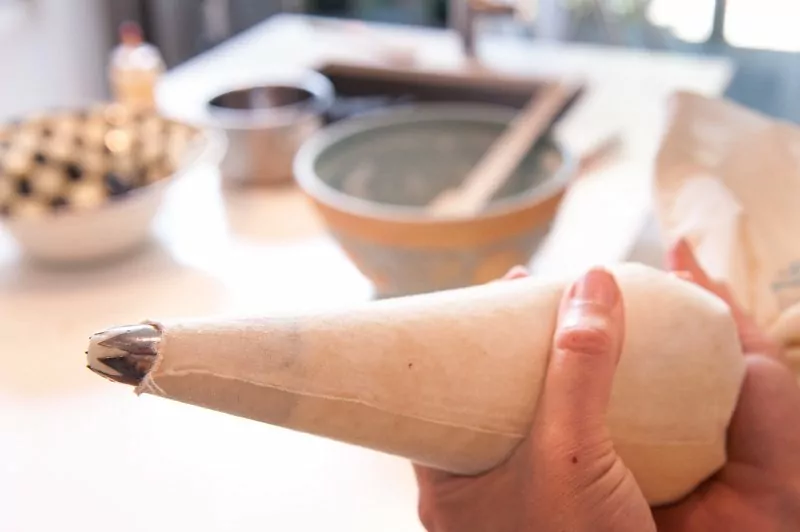 The piping bag with the star tip filled with churro batter.