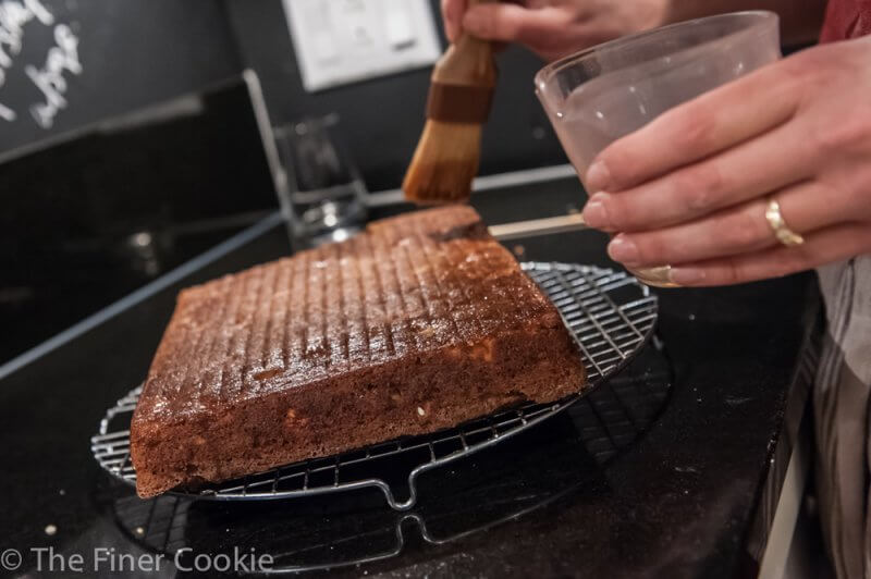 Brushing the baked cake with syrup.