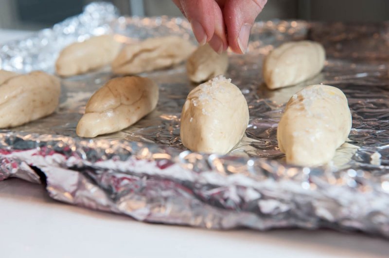 Salting the glazed pretzel breads.