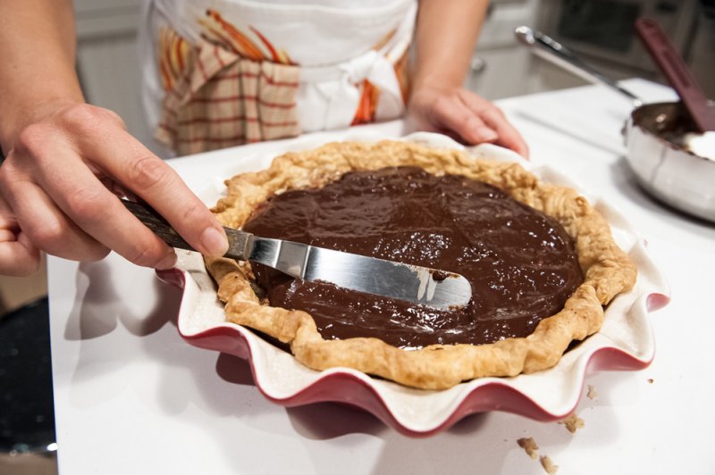 Spreading the chocolate ganache over the filling.