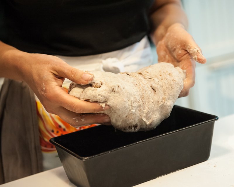 Dropping the bread dough into the loaf pan.