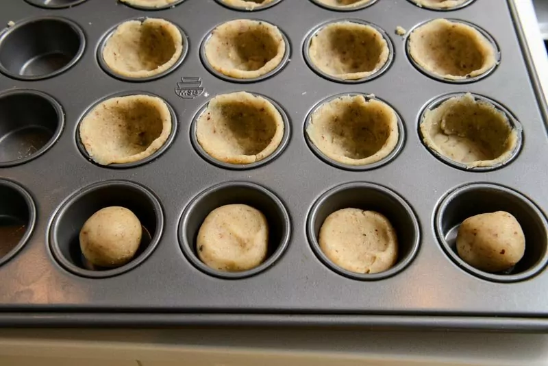 Filling the cups with cookie crust dough.