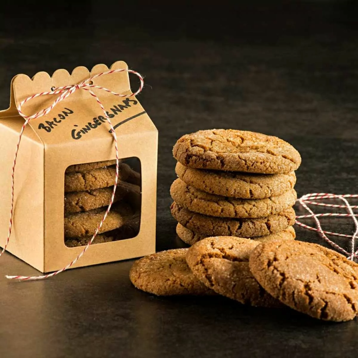 Bacon Fat Gingersnaps stacked on table next to a gift box