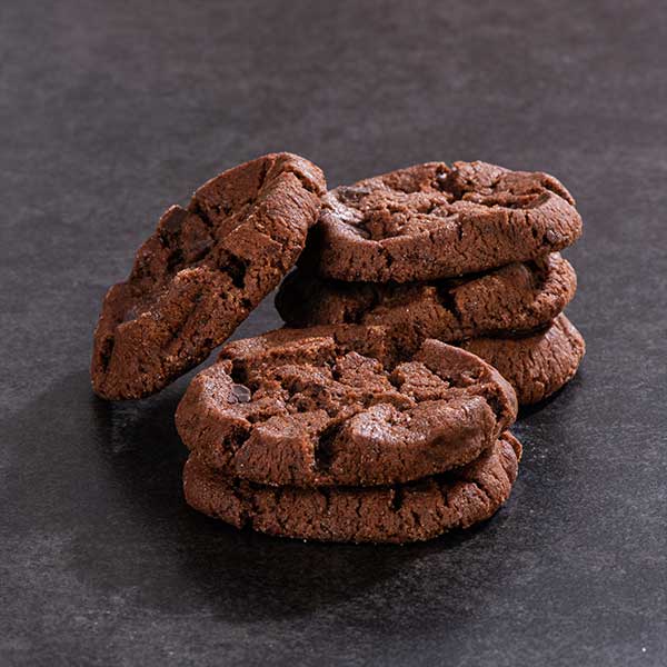 Molé Cookies stacked on decorative plate with cinnamon sticks and chipotle pepper