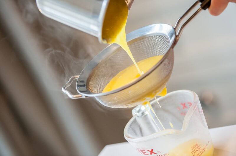 Straining the lemon curd while still hot.