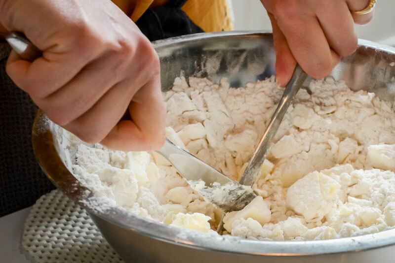 Cutting the butter into the flour and cream cheese.
