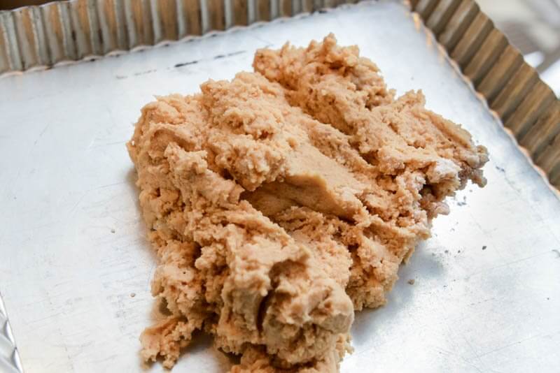 Hazelnut Cookie Dough spread into the 9″ square tart pan.