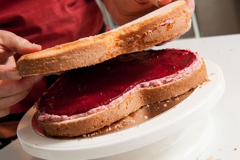 Laying the top layer of the cake over the filling.