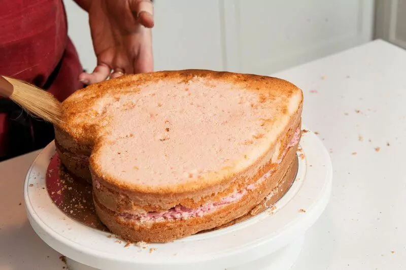 Brushing as many crumbs off the top of the cake as possible.