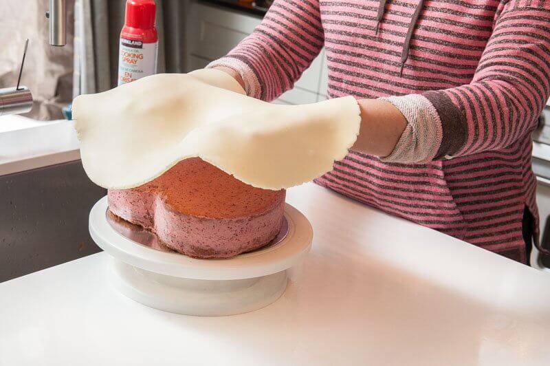 Positioning the fondant over the cake.