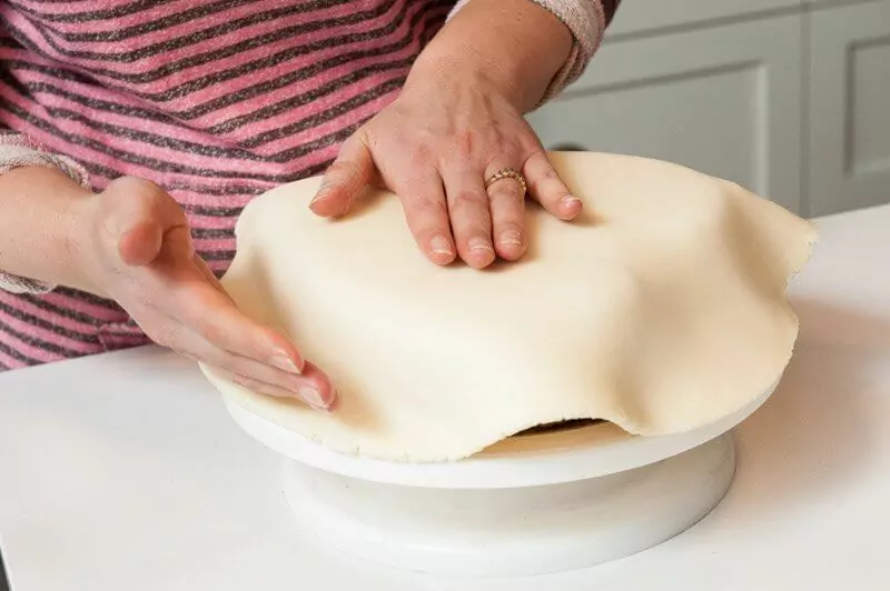 Beginning to form the fondant over the cake.