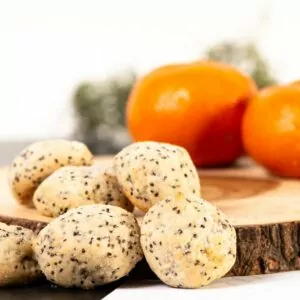 Orange Chia Seed Cookies placed on wooden log cutting board with decorative oranges