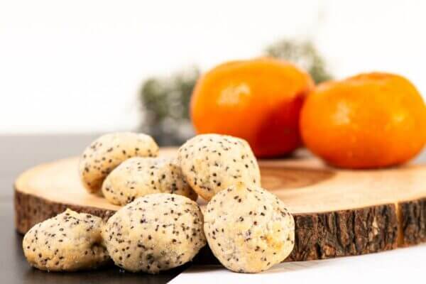 Orange Chia Seed Cookies placed on wooden log cutting board with decorative oranges